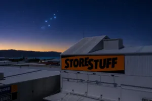 StoreStuff Wellington storage facility under a pre-dawn sky with the Matariki star cluster rising over the hills