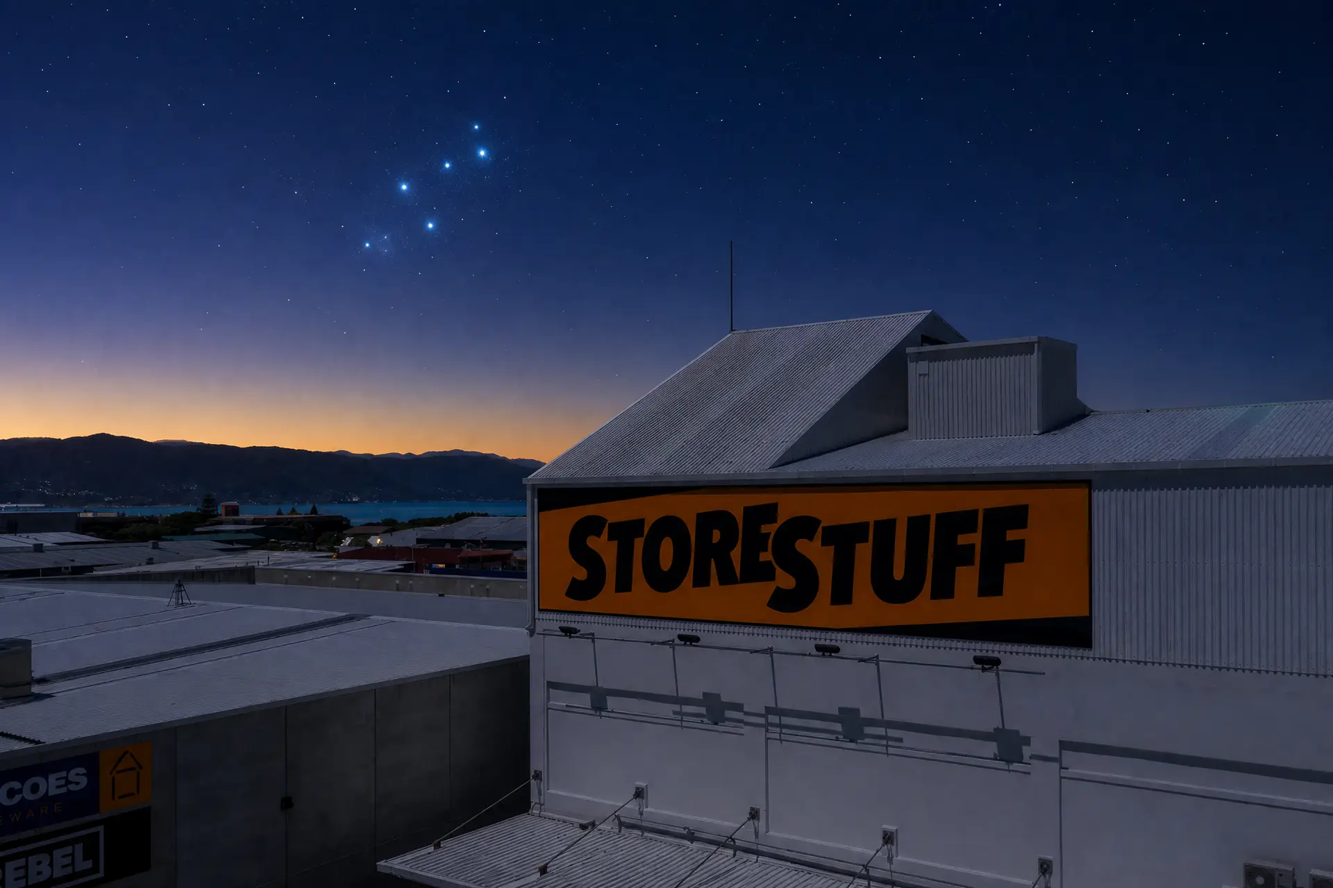 StoreStuff Wellington storage facility under a pre-dawn sky with the Matariki star cluster rising over the hills
